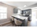 Bright kitchen featuring grey cabinetry, quartz countertops and seating for three at the counter at 10353 Liverpool Way, Indianapolis, IN 46236