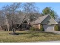 View of home with brick facade, arched entryway, with a well-manicured lawn and mature trees at 1110 Butternut Dr, Columbus, IN 47201