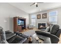 Cozy living room with a fireplace, ceiling fan, plush leather sofas and bright windows at 12610 Broadmoor N Ct, Fishers, IN 46037