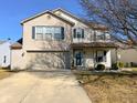 Two-story home featuring a brick facade, attached garage and covered porch with well-maintained lawn at 14243 Holly Berry Cir, Fishers, IN 46038