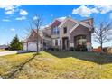 Beautiful two-story home with brick and stone exterior, manicured lawn, and mature trees at 14347 Camelot House Way, Fishers, IN 46037