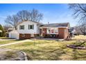 Inviting two-story home featuring a brick facade, detached garage, well-manicured lawn, and cozy front porch seating at 229 W Taylor St, Pendleton, IN 46064