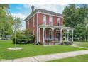 Classic brick home featuring a large front porch, green lawn, and inviting curb appeal at 300 S Market St, Thorntown, IN 46071