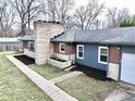An aerial view of this single-story home with manicured lawn, stone chimney, and attached garage at 405 W 73Rd St, Indianapolis, IN 46260