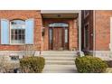 Elegant front entrance showcasing a wooden door with glass detailing and manicured landscaping at 438 E Vermont St, Indianapolis, IN 46202