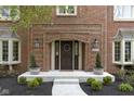 Close-up of a brick home's entrance with a decorative front door, sidelights, and landscaping at 4978 St Charles Pl, Carmel, IN 46033