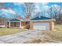 Side view of a single-story brick home, showing a cracked driveway and blue trim at 5683 Boy Scout Rd, Lawrence, IN 46226