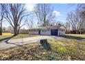 Attractive single-story residence with a gray brick exterior, paved driveway, and an attached garage at 6603 Iona Rd, Indianapolis, IN 46203