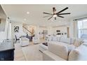 Bright, open-concept living area with a large sectional sofa, hardwood floors, and modern ceiling fan at 7256 Firestone Rd, Whitestown, IN 46075