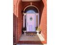 Close-up of the brick-framed front door with decorative glass, welcome mat, and potted plants at 10476 N Prairie Hills Dr, Mooresville, IN 46158