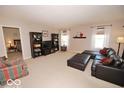 Spacious living room with neutral carpeting, dark wood furnishings, a large sectional sofa, and natural light from windows at 11026 Cool Winds Way, Fishers, IN 46037