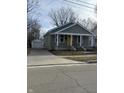 Quaint home with a yellow front door, cozy front porch, and a detached one car garage at 1237 E 29Th St, Anderson, IN 46016
