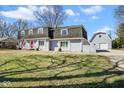 Charming home with detached garage, red front door, grey brick, shutters, and a well-maintained lawn at 1310 Bowman Dr, Greenfield, IN 46140
