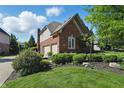 Brick home featuring a two-car garage, beautiful landscaping, and green lawn at 2750 Joshua Dr, Carmel, IN 46033