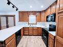 Kitchen with wood cabinets, white countertops, black appliances, and modern track lighting at 4109 E Epler Ave, Indianapolis, IN 46237