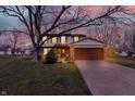 Charming two-story home featuring a brick facade, attached two-car garage, and landscaped front yard at dusk at 7344 Monon Cir, Indianapolis, IN 46256