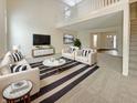 Bright living room with soaring ceilings, large windows, modern furniture, and a staircase leading to the second floor at 825 Treyburn Green Dr, Indianapolis, IN 46239