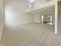 Bright living room with soaring ceilings, large windows, carpet floors, and a staircase leading to the second floor at 825 Treyburn Green Dr, Indianapolis, IN 46239