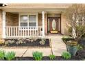 Inviting front porch with white railing and detailed front door, surrounded by manicured landscaping at 12512 Geist Cove Dr, Indianapolis, IN 46236