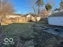 Spacious backyard with a mix of grass, exposed dirt, a wooden fence, and partial concrete at 1827 N Whittier Pl, Indianapolis, IN 46218