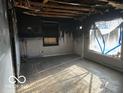 Damaged living room featuring hardwood floors and a destroyed ceiling at 1827 N Whittier Pl, Indianapolis, IN 46218