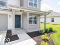 View of the covered front porch with gray columns, landscaping, and a dark blue front door at 3328 Stafford St, Sheridan, IN 46069