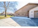 Attached two-car garage with a concrete driveway, exterior lighting, and neutral brown coloring at 3535 Woodglen Way, Anderson, IN 46011