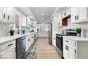 Galley kitchen with white cabinetry, stainless steel appliances, and wood-look floors throughout at 5004 Boardwalk Pl, Indianapolis, IN 46220