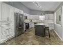 Bright kitchen featuring stainless steel refrigerator, white cabinets, and a functional center island at 5503 Thompson Park Blvd, Indianapolis, IN 46237