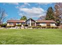 Ranch-style home featuring a well-manicured front yard, large windows, and mature landscaping at 6114 Brokenhurst Rd, Indianapolis, IN 46220