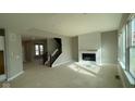 Open concept living room boasts a fireplace, staircase, and large windows providing natural light at 6323 Willow Branch Way, Plainfield, IN 46168