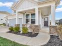 Covered front porch with stone accents, a white rocking chair, and manicured landscaping at 6915 Diamondleaf Way, Brownsburg, IN 46112