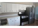 Well-lit kitchen with white cabinets, white countertop, stainless steel appliances, and decorative knobs at 7625 Partridge Rd, Indianapolis, IN 46227
