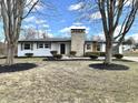 Charming single-story home featuring a prominent stone chimney and mature trees, set in a well-kept front yard at 8795 Carrollton Ave, Indianapolis, IN 46240