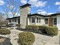 Charming single-story home with a stone chimney and black accents in a well-maintained landscape at 8795 Carrollton Ave, Indianapolis, IN 46240