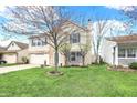 Inviting two-story home with green lawn, bench and landscaping offers a welcoming exterior at 9243 Crossing Dr, Fishers, IN 46037