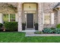 Elegant front entrance with a dark door, decorative columns, and manicured landscaping at 10576 Greenway Dr, Fishers, IN 46037
