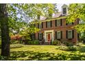 Charming brick home featuring a bright red front door and well-manicured landscaping at 1409 S Harmony Trl, Greenfield, IN 46140