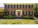 Close up of brick home featuring a bright red front door and manicured bushes at 1409 S Harmony Trl, Greenfield, IN 46140
