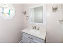 Cozy half bathroom featuring stylish vanity, decorative mirror, sconces, and sailboat themed stained glass window at 14485 Oak Ridge Rd, Carmel, IN 46032