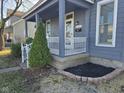 Charming front porch with white railing, lush greenery, and a freshly mulched garden bed at 1828 Central Ave, Columbus, IN 47201