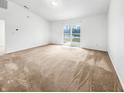 Spacious room with neutral walls and carpet, leading to a sliding glass door with backyard access at 1914 Kingen Dr, Greenfield, IN 46140