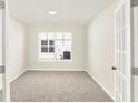 A brightly lit room with neutral walls, carpet and a view of the backyard through a window at 19599 Atwater Ave, Sheridan, IN 46069