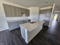 Bright kitchen boasts a central island, granite countertops, ample storage, gray cabinets, and dark hardwood floors at 2254 Oakmont Dr, Plainfield, IN 46168