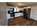 Modern kitchen with stainless steel appliances, white cabinets, dark backsplash and hardwood floors at 5061 N 200 W, Columbus, IN 47201