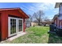 The backyard features a red shed with French doors, adjacent to green grass and an AC unit at 5414 Honey Comb Ln, Indianapolis, IN 46221
