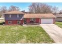 Charming multi-level home featuring a brick facade, attached garage and well-manicured lawn at 5414 Honey Comb Ln, Indianapolis, IN 46221