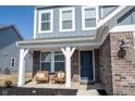 Inviting front porch with brick accents and comfortable seating, perfect for relaxing outdoors at 5462 Wood Spg Ln, McCordsville, IN 46055