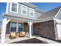 Charming front porch featuring brick accents, two inviting chairs, and stylish architectural details at 5462 Wood Spg Ln, McCordsville, IN 46055