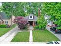 Quaint home featuring a brick facade, landscaped yard, and a inviting front porch, framed by lush trees at 6162 Carrollton Ave, Indianapolis, IN 46220
